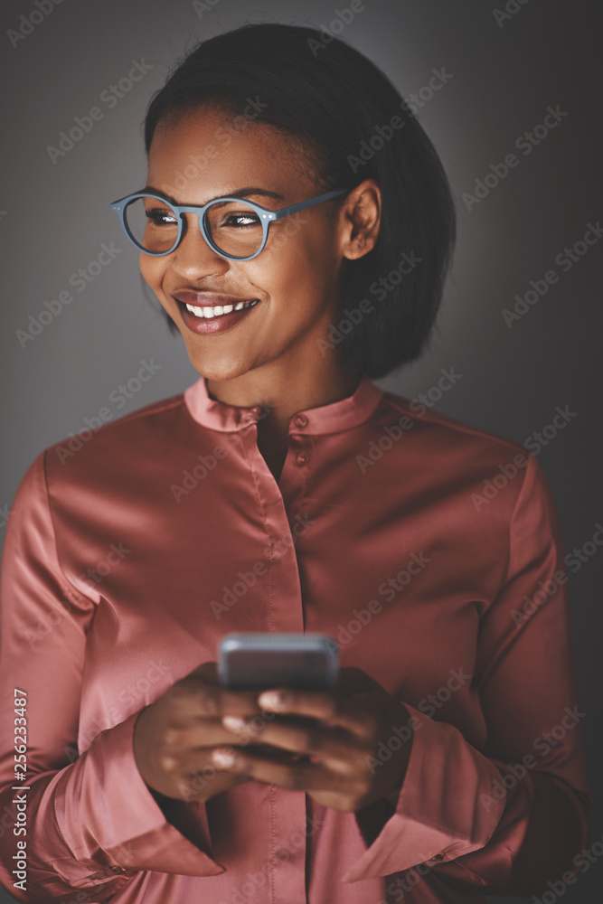 Young African businesswoman using her cellphone against a gray b