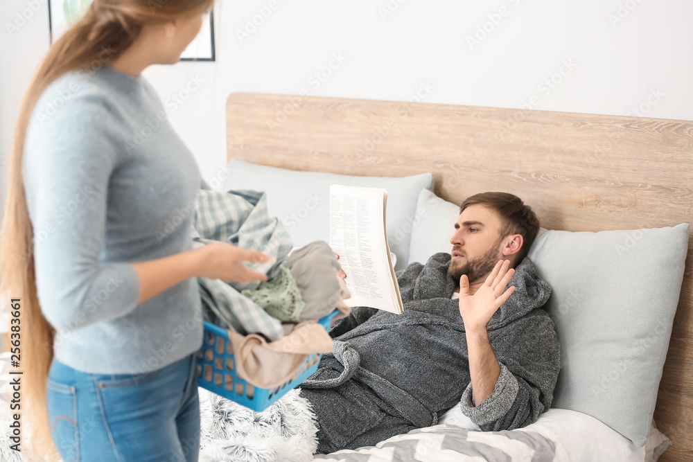 Housewife asking for help her lazy husband lying on bed at home