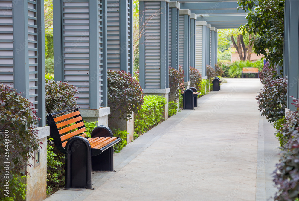 Empty outdoors promenade with resting chairs and bush in a new park,China