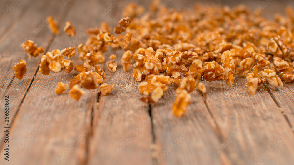 MACRO: Cinematic shot of walnut kernels sliding down the wooden kitchen table.