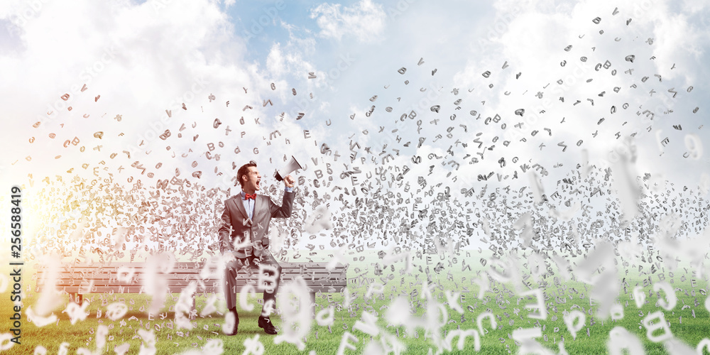 Businessman in summer park announcing something in loudspeaker and symbols fly around