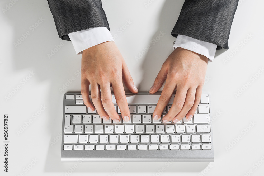 Closeup of businesswoman hand typing on keyboard with mouse on wood table