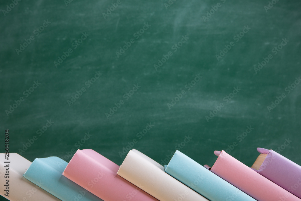 Education and reading concept - group of colorful books on the wooden table in the classroom, blackb