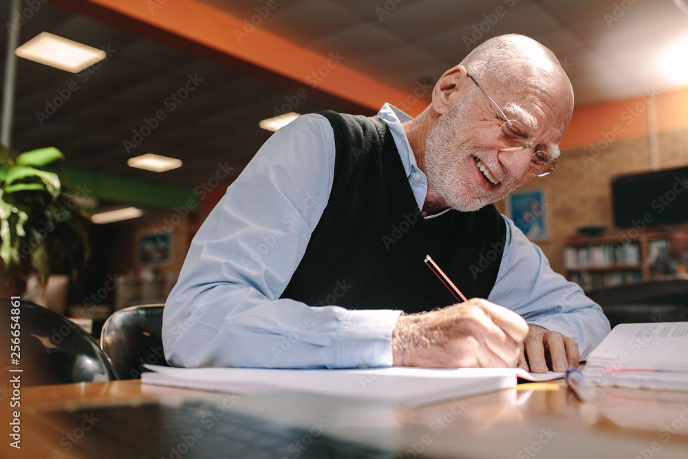 Senior man making notes in classroom