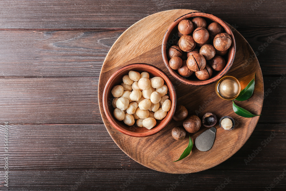 Bowls with macadamia nuts and oil on wooden table