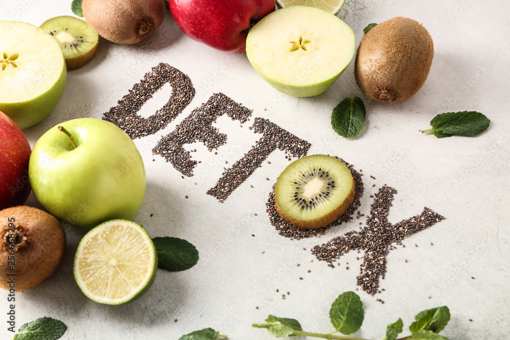 Word DETOX with fresh fruits on light background