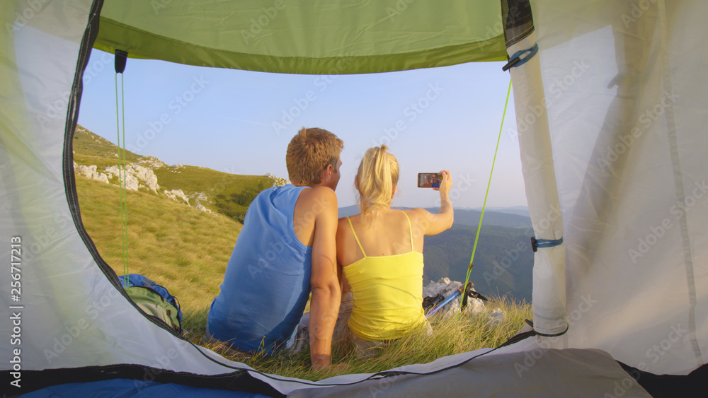 CLOSE UP: Young man and woman taking a photo together during a hiking adventure.