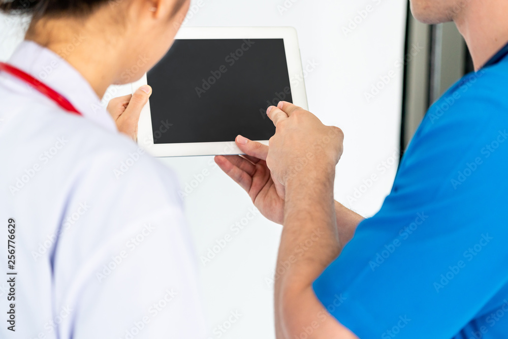 Female doctor using tablet computer while discussing with another doctor at the hospital. Medical he