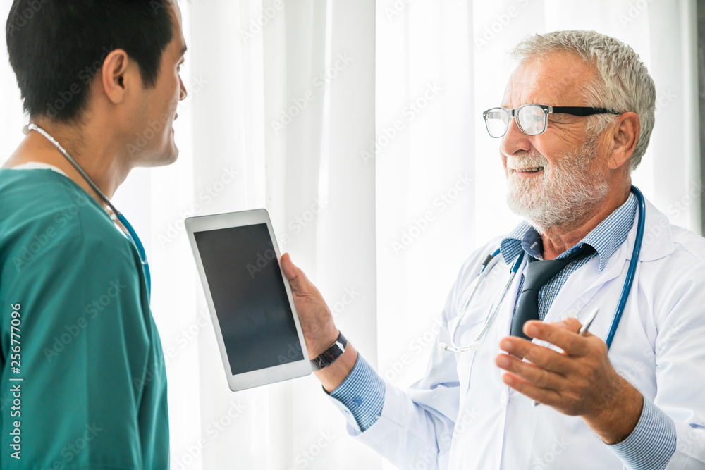 Senior male doctor using tablet computer while discussing with another doctor at the hospital. Medic