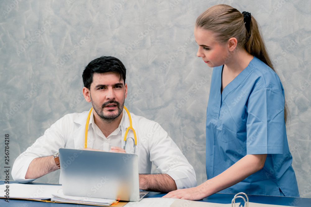 Happy doctor and nurse working with laptop computer in hospital office. Healthcare and medical conce