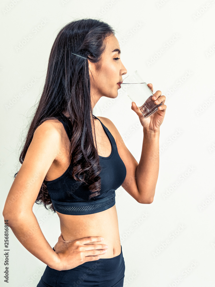 Woman in sportswear drinking water in a fitness gym. Healthy lifestyle and hydration concept.