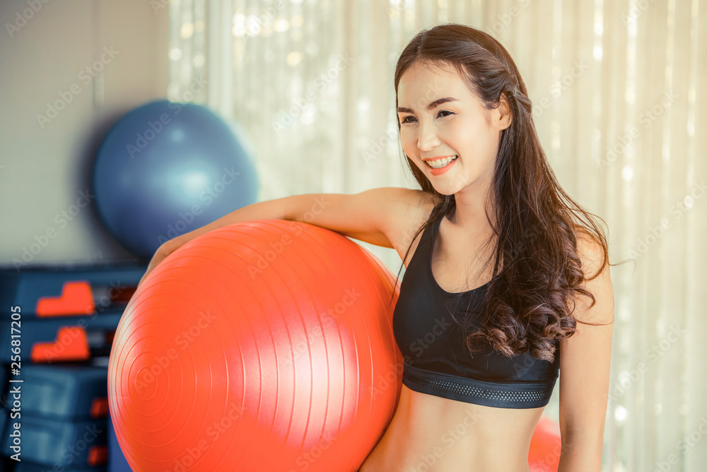 健身中心漂亮年轻女子用健身球做普拉提运动。健康的生活方式