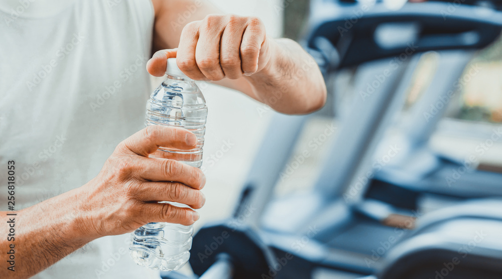 Senior man drink mineral water in gym fitness center after exercise. Elderly healthy lifestyle.