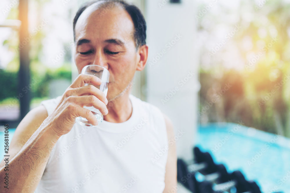 老年人运动后在健身房健身中心喝矿泉水。老年人健康的生活方式。