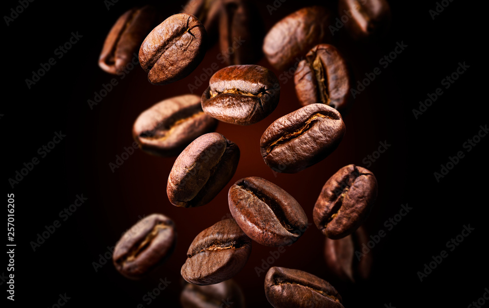 Roasted falling or flying coffee beans on black background, close up, brown texture