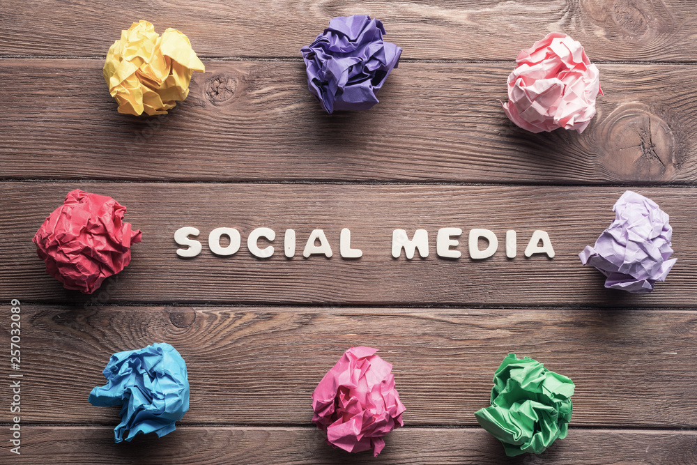 Social media phrase and colorful crampled paper ball placed in circle on wooden table