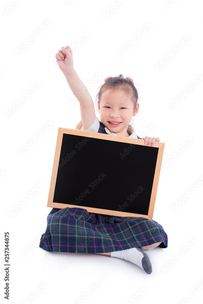 Full length of shoolgirl wearing uniform and holding blackboard sitting over white background