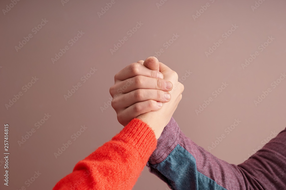 Man and woman holding hands on color background