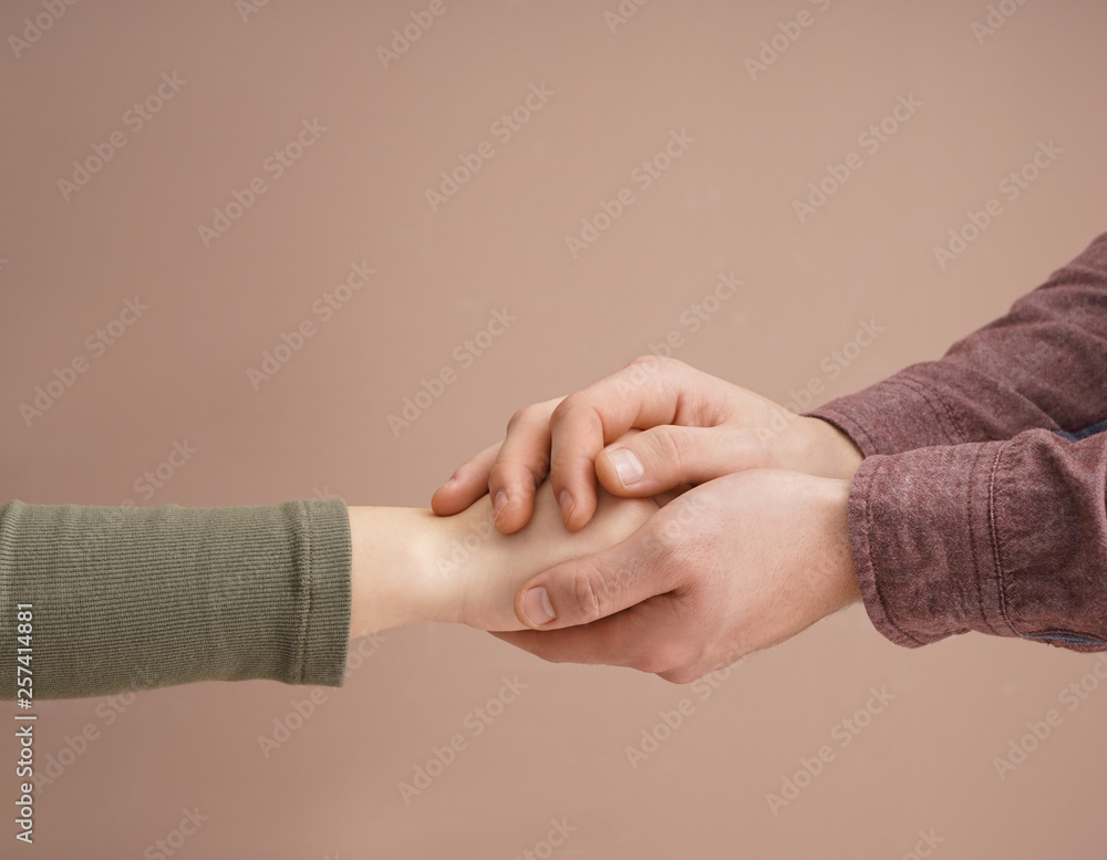 Hands of man comforting young woman on color background