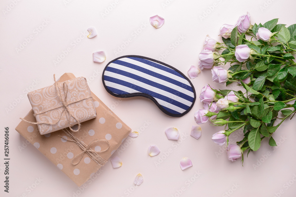 Composition with sleep mask, flowers and gifts on color background