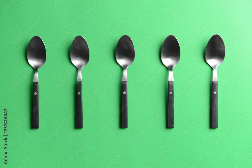 Metal spoons on color background