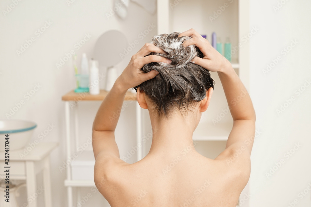 Young woman washing hair in bathroom