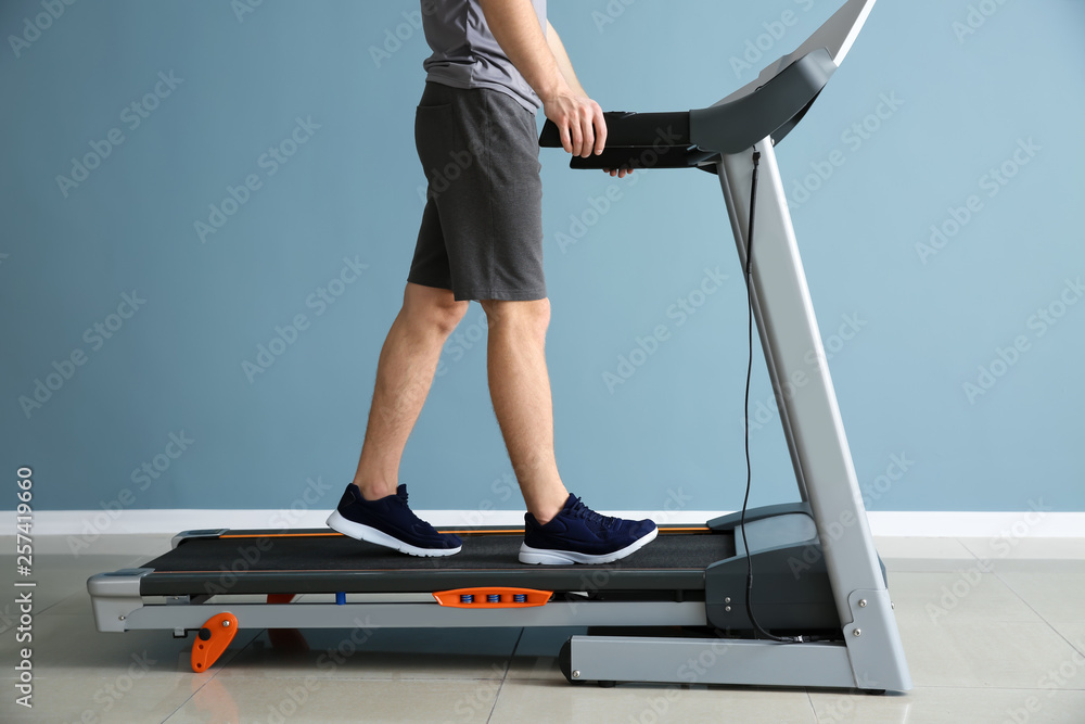 Sporty young man training on treadmill in gym