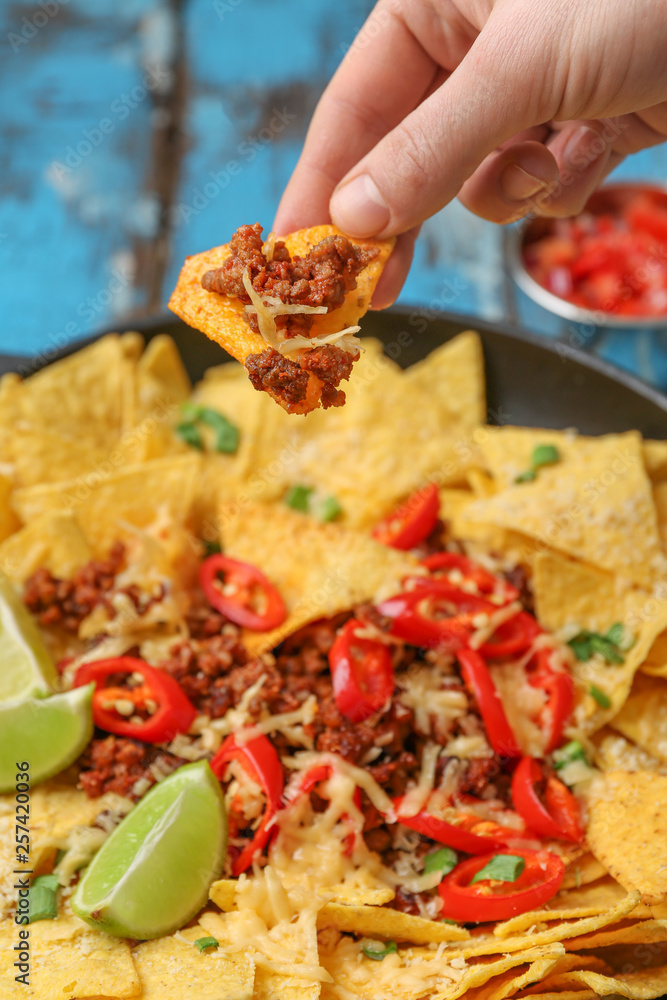 Woman eating tasty nachos with minced meat, closeup