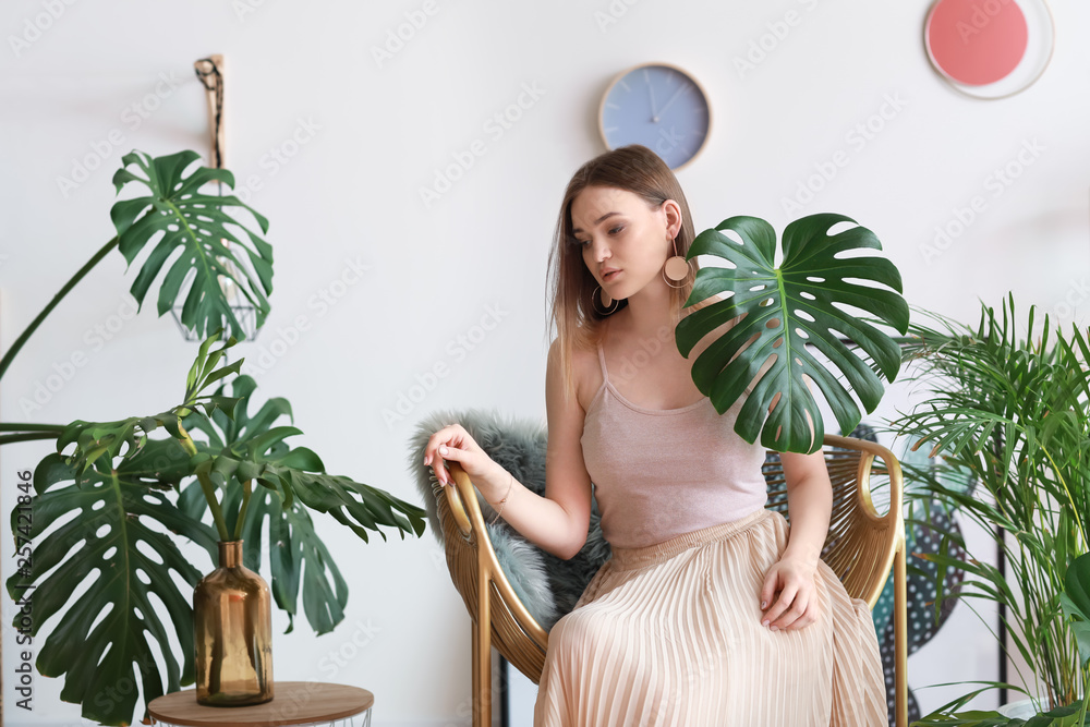 Portrait of beautiful woman with green tropical plants indoors