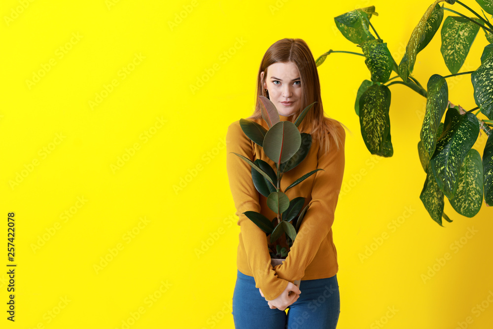 Portrait of beautiful woman with green tropical plants on color background