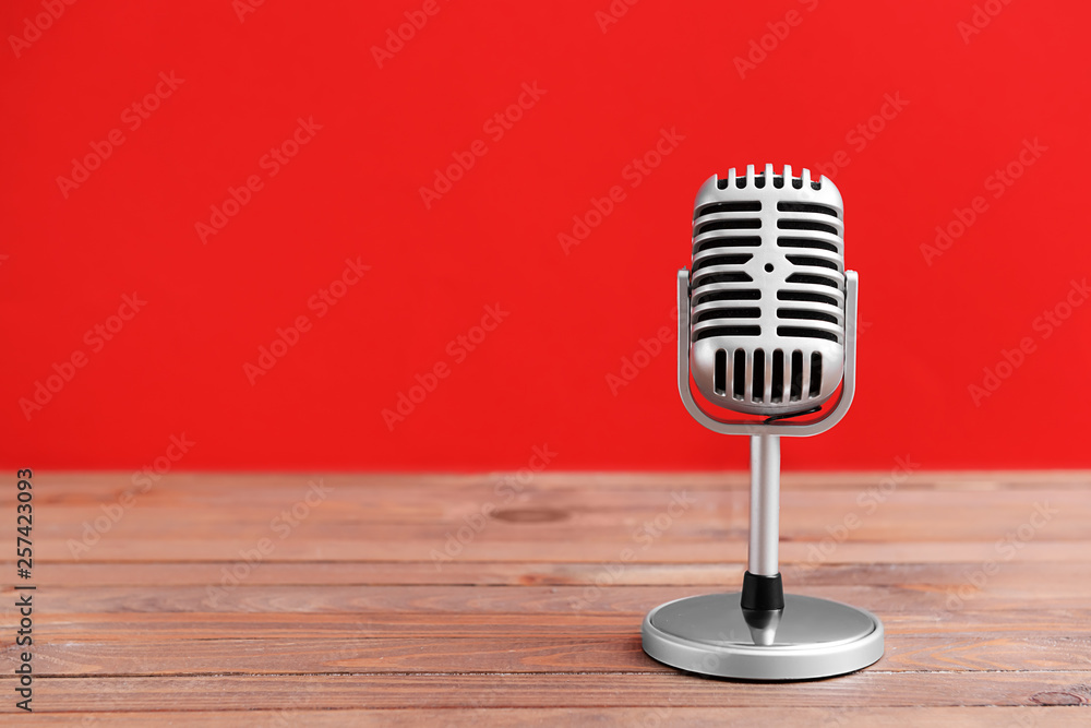 Retro microphone on table against color background