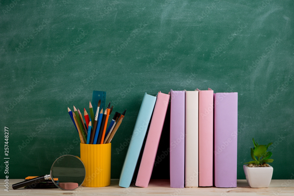 Education and reading concept - group of colorful books on the wooden table in the classroom, blackb