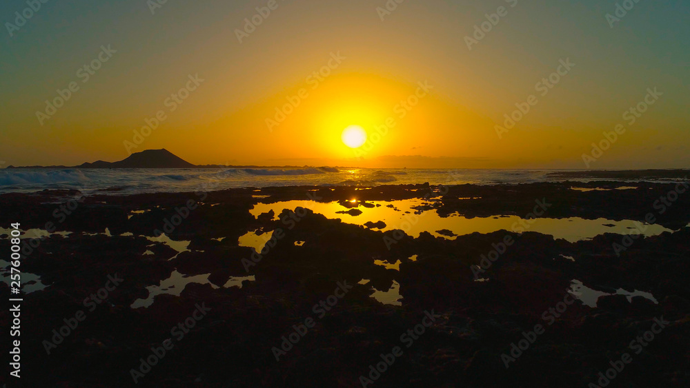 透镜闪光：在一个金色的夏夜，小海浪冲刷着岩石海岸。