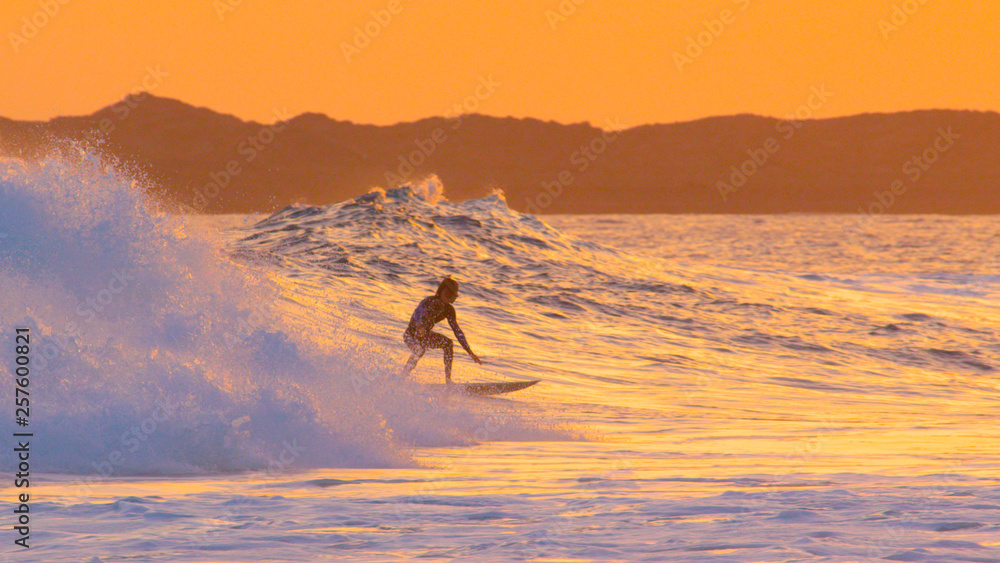 Surfer dude crouches on his surfboard while surfing a beautiful breaking wave