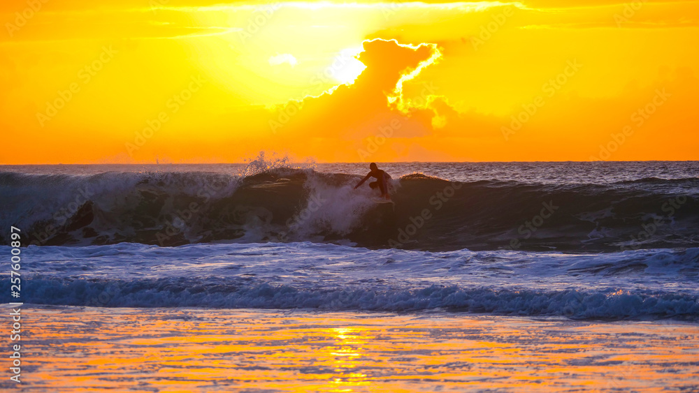 Pro male rider surfing cool ocean waves to remote beach in the early morning