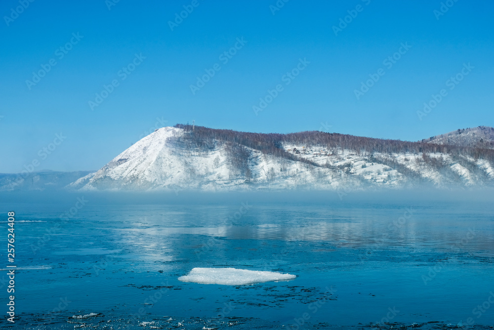 冬季河流中漂浮的浮冰，以雪山为背景