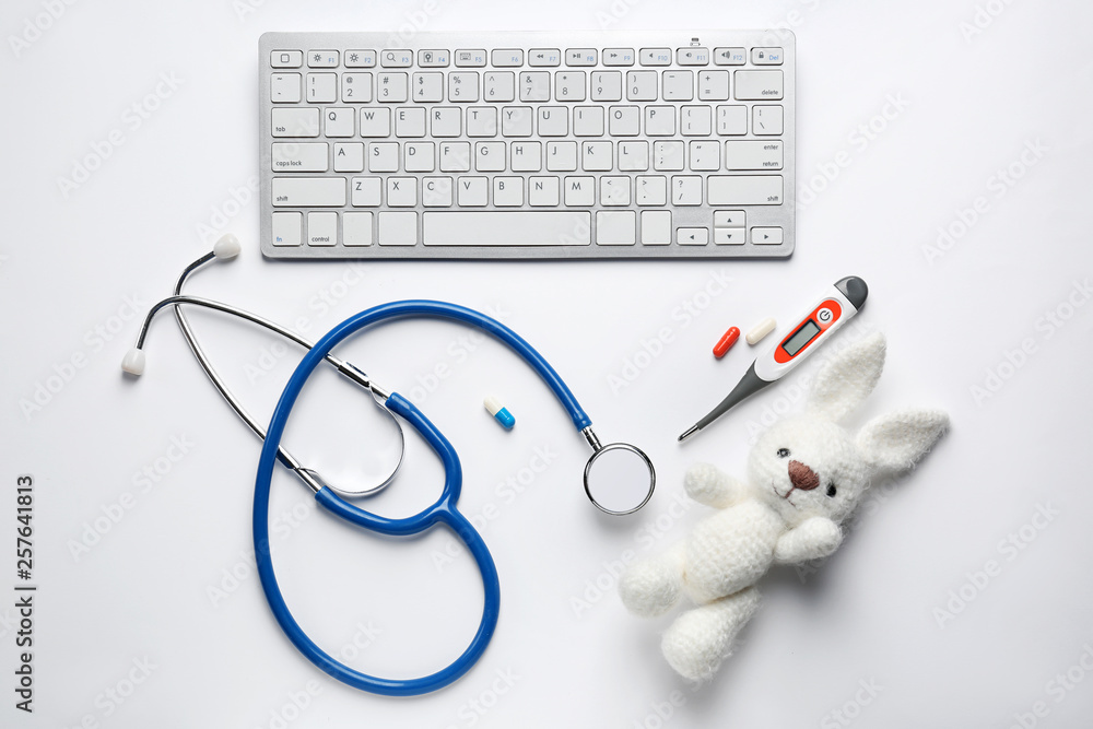 PC keyboard, stethoscope, thermometer and toy on white background