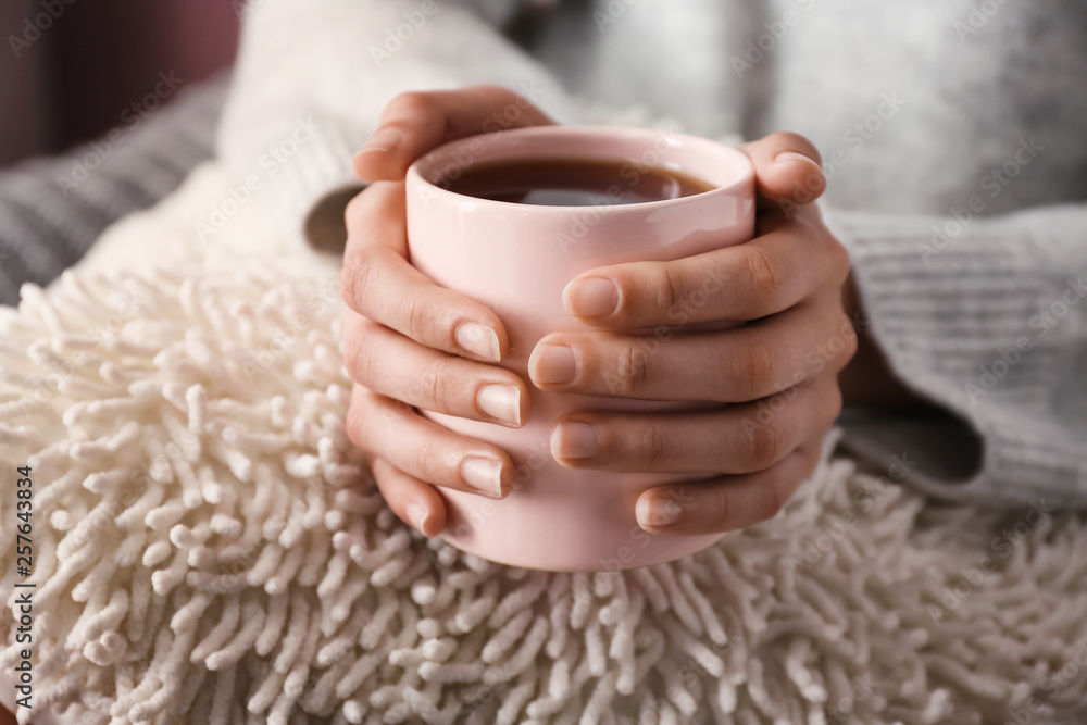 Young woman drinking hot tea at home, closeup