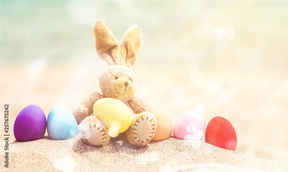 Easter bunny and color eggs on the sandy beach by the ocean