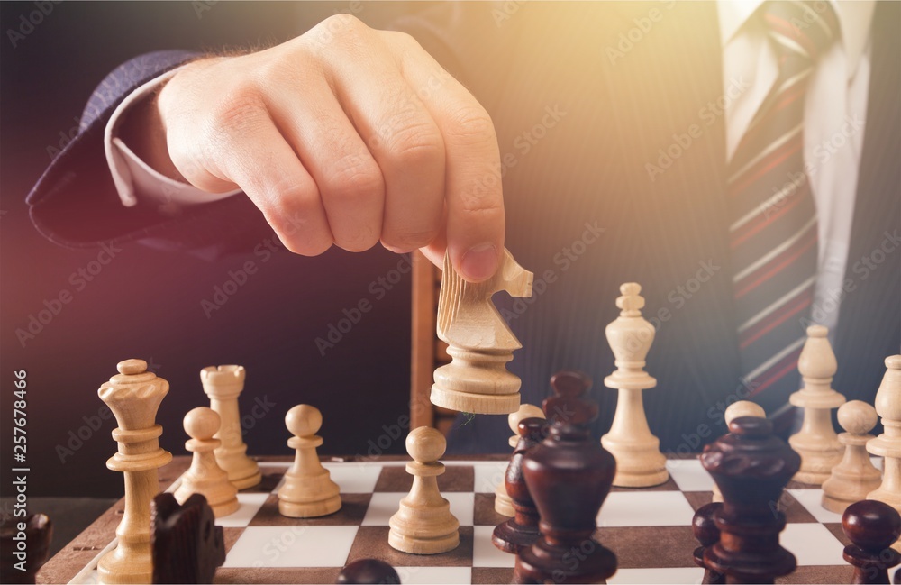 Businessman Hand Holding a Chess Piece on a Chessboard