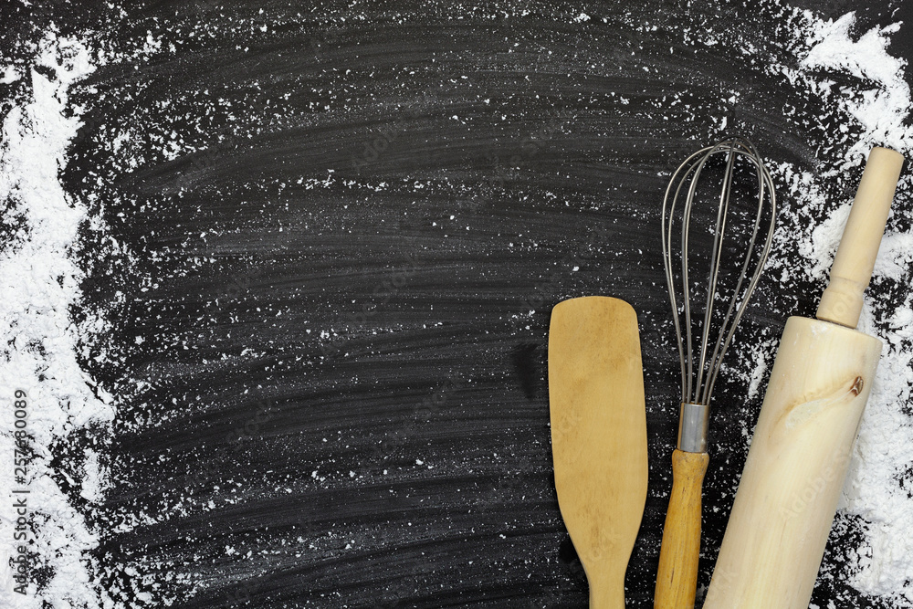 sprinkle wheat flour with copy space for text on dark black wood background, top view for cooking do