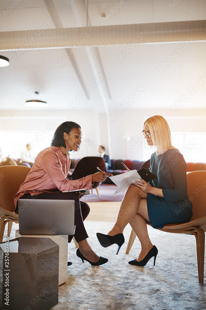 Two businesswomen going over documents together in an office