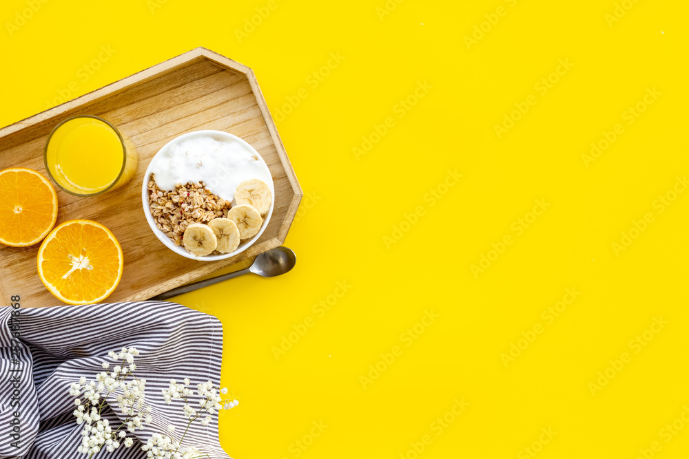 Bright breakfast with granola and orange juice on yellow background top view mockup