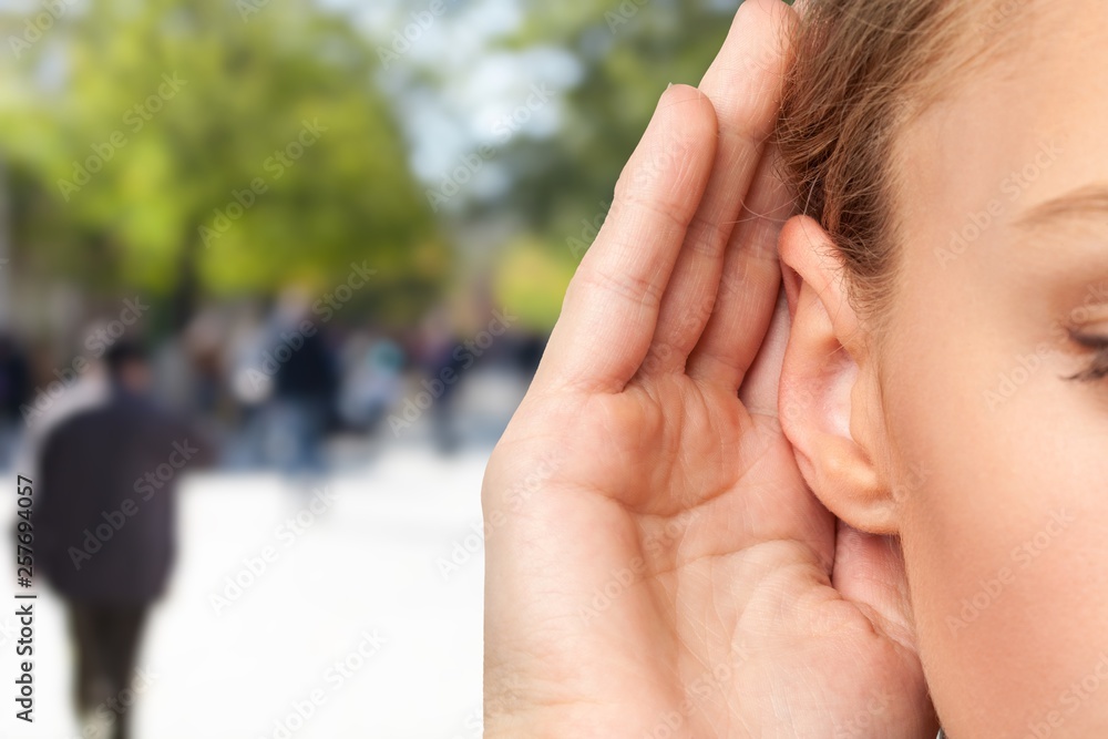 Girl listening with her hand on an ear cose up