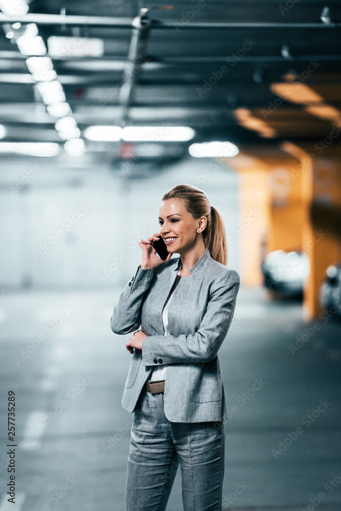 Businesswoman talking on smartphone in parking garage.