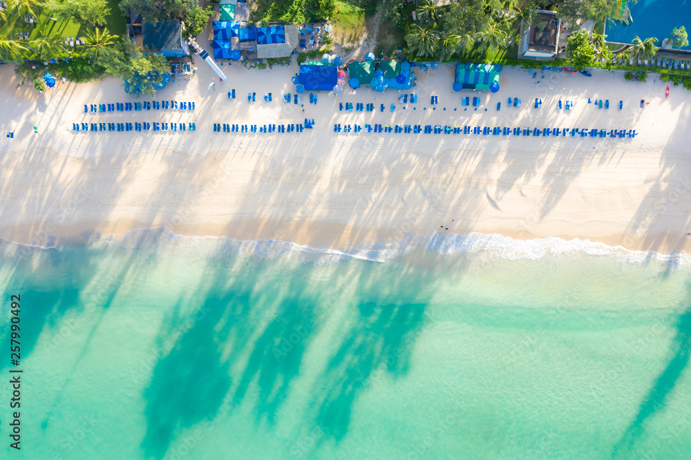 Aerial view of sandy beach with tourists swimming in beautiful clear sea water in Phuket, Thailand.