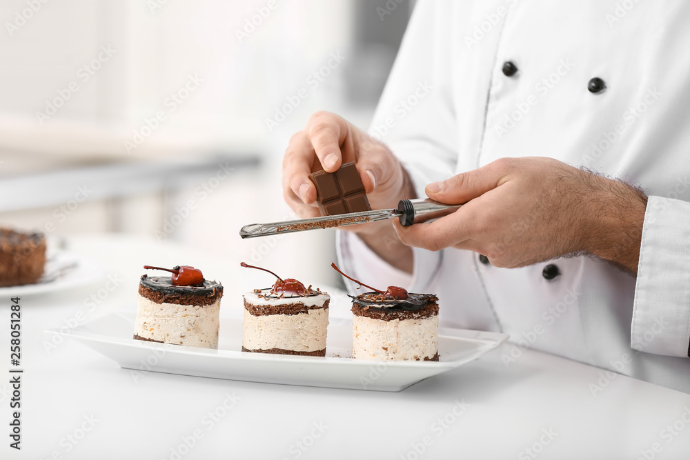 Male confectioner decorating tasty dessert in kitchen, closeup