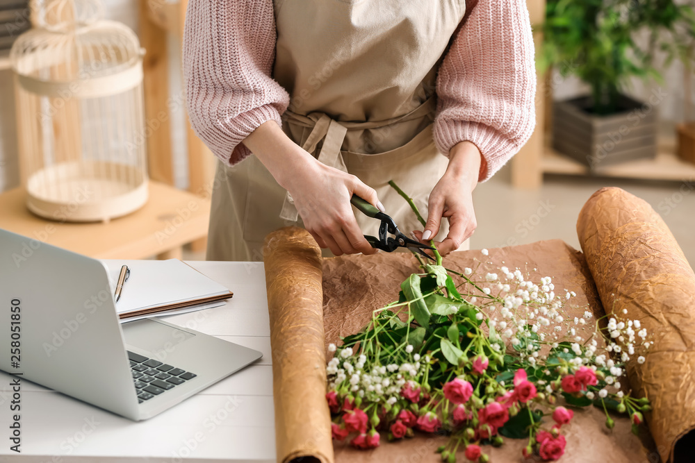 Beautiful female florist working at table in shop, closeup