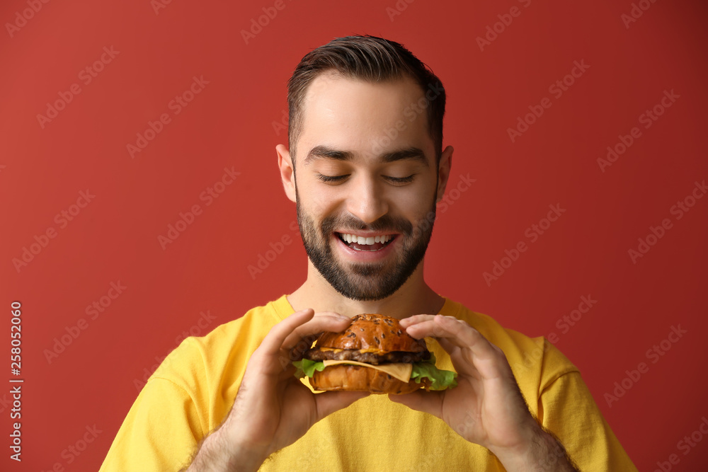 Man with tasty burger on color background