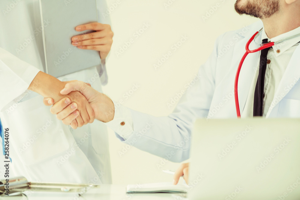 Doctor at the hospital giving handshake to another doctor showing success and teamwork of profession